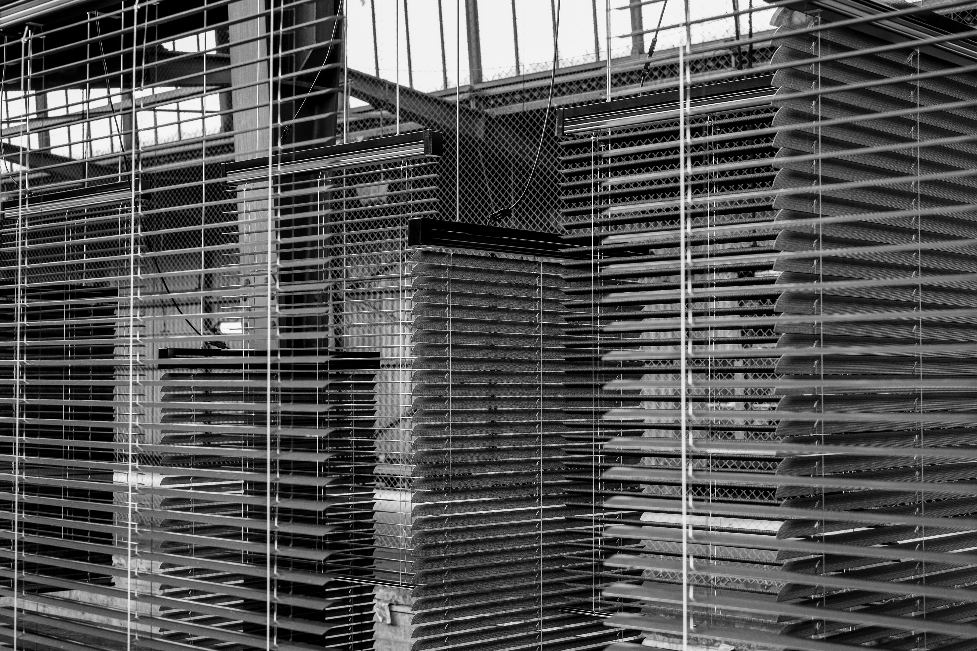 Close-up view of partially open window blinds casting shadows and patterns.