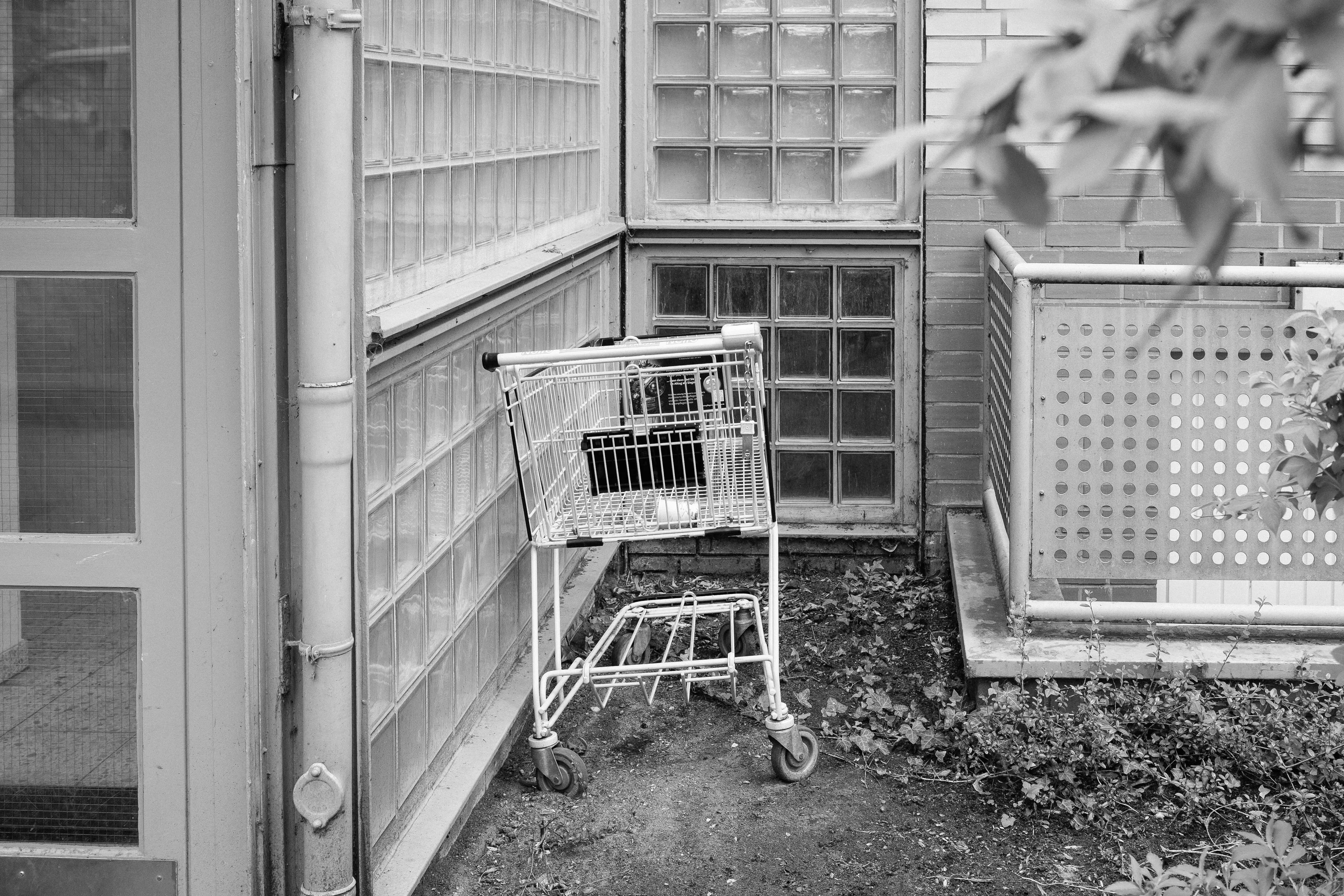 Abandoned shopping cart in a corner with glass block walls.