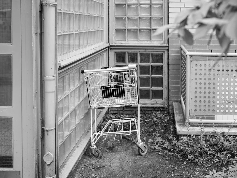 Abandoned shopping cart in a corner with glass block walls.