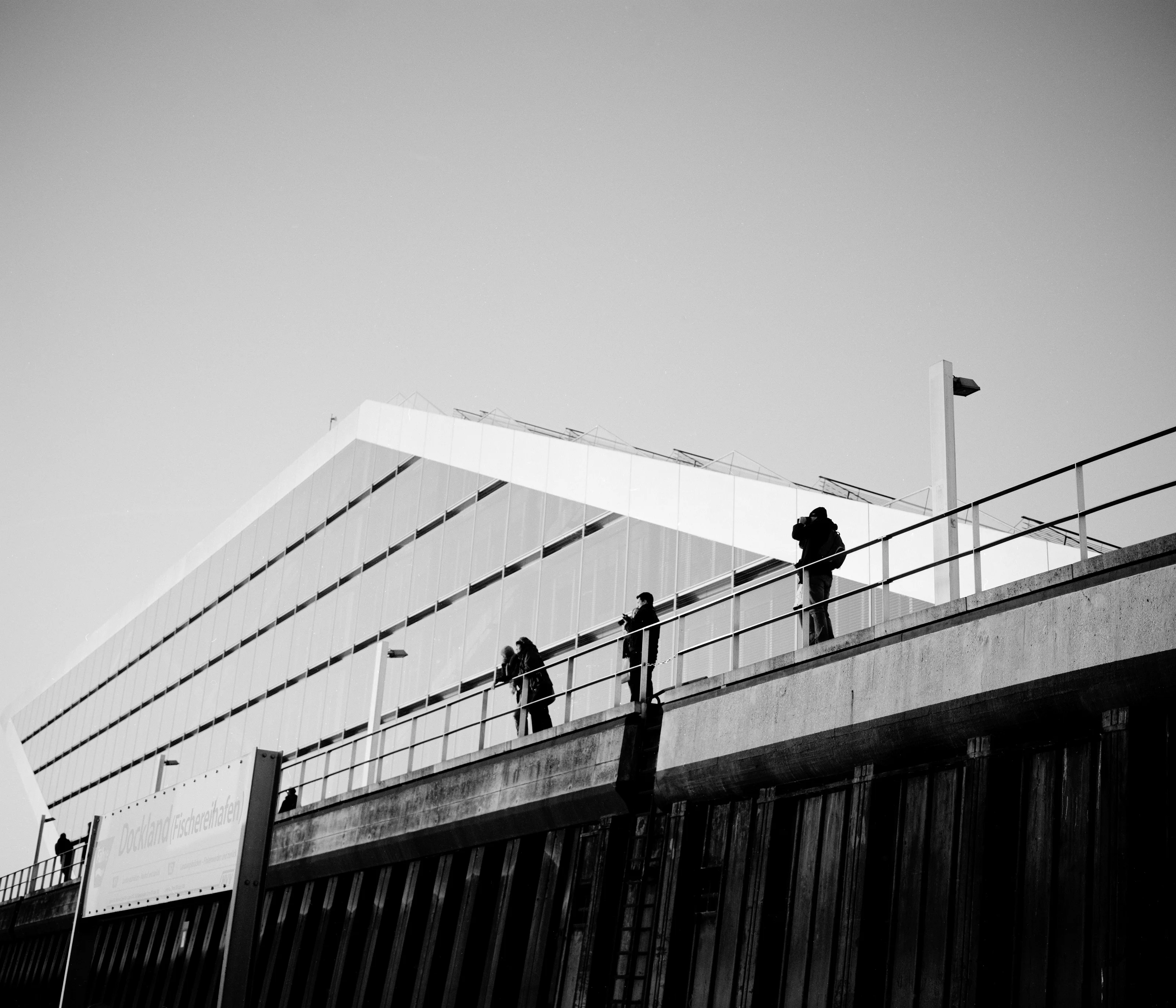 People standing on a walkway in front of a modern, angular building.