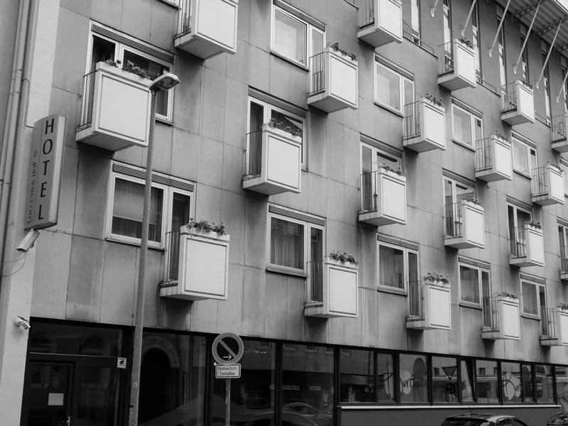 A black and white photo of a hotel facade with multiple small balconies.