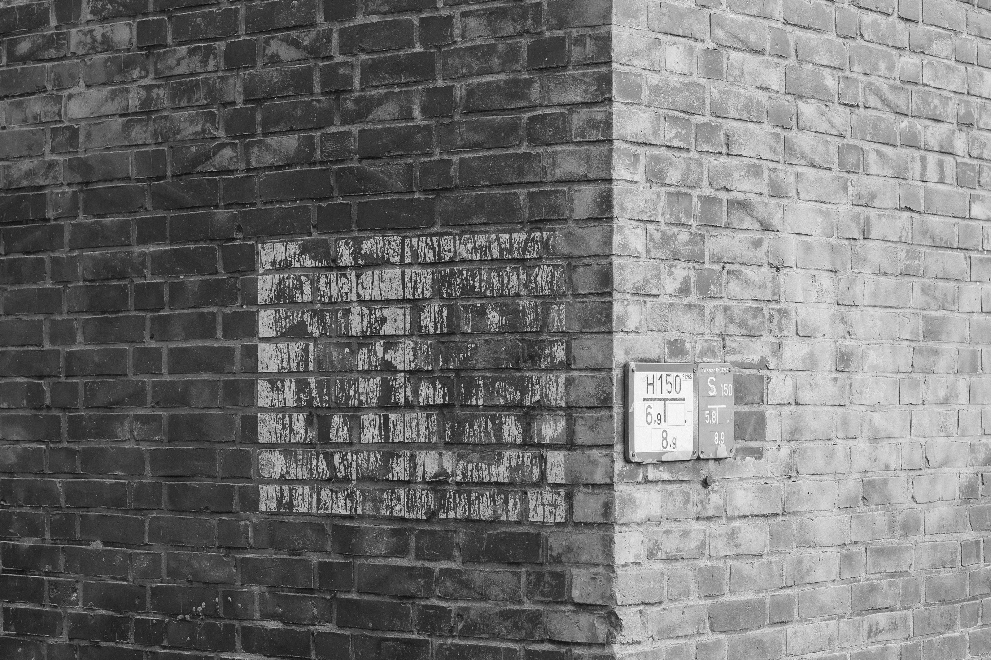 Corner of a brick wall with painted and mounted signs.