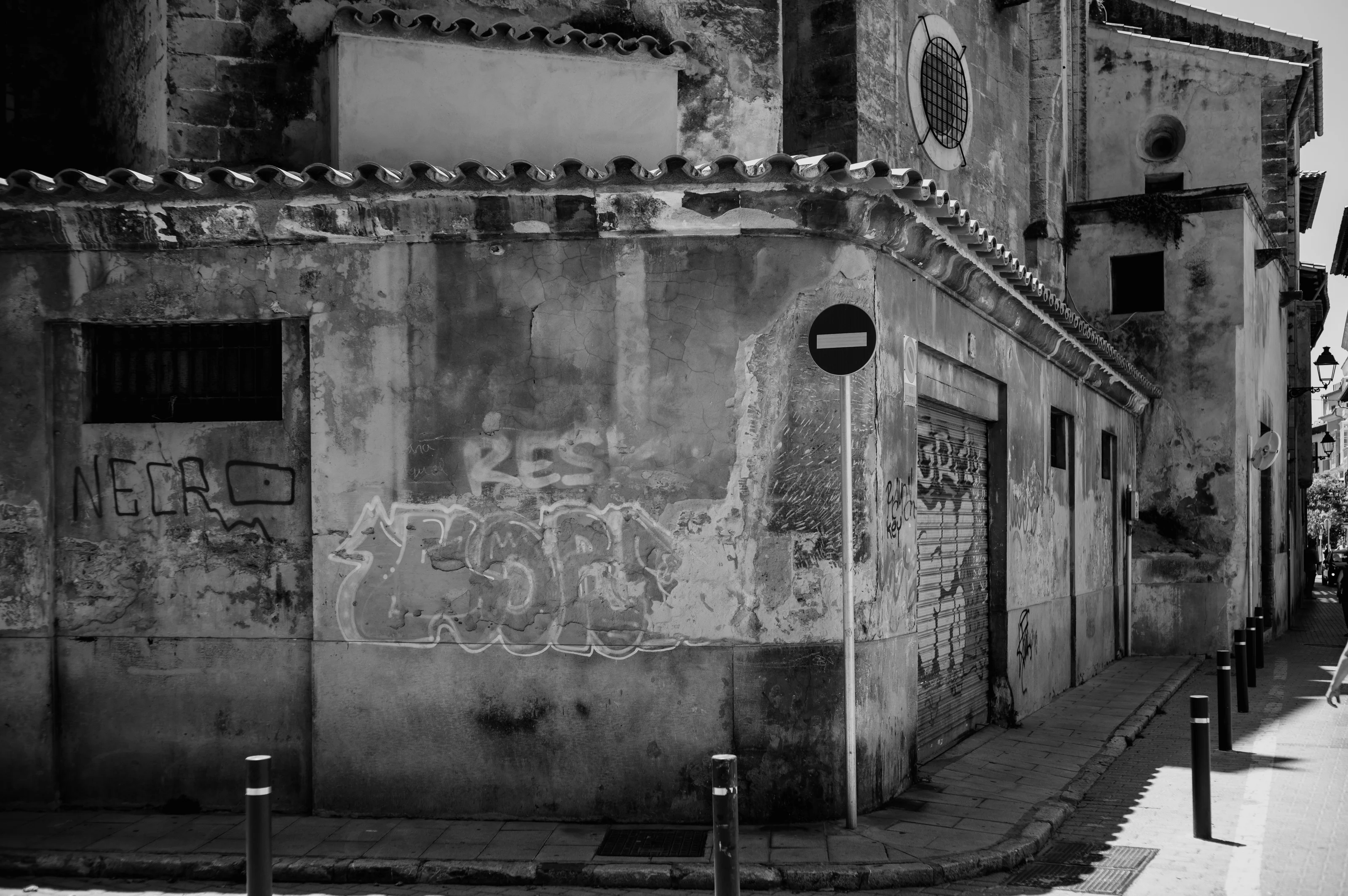 A weathered building with graffiti and a no-entry sign on a narrow street.