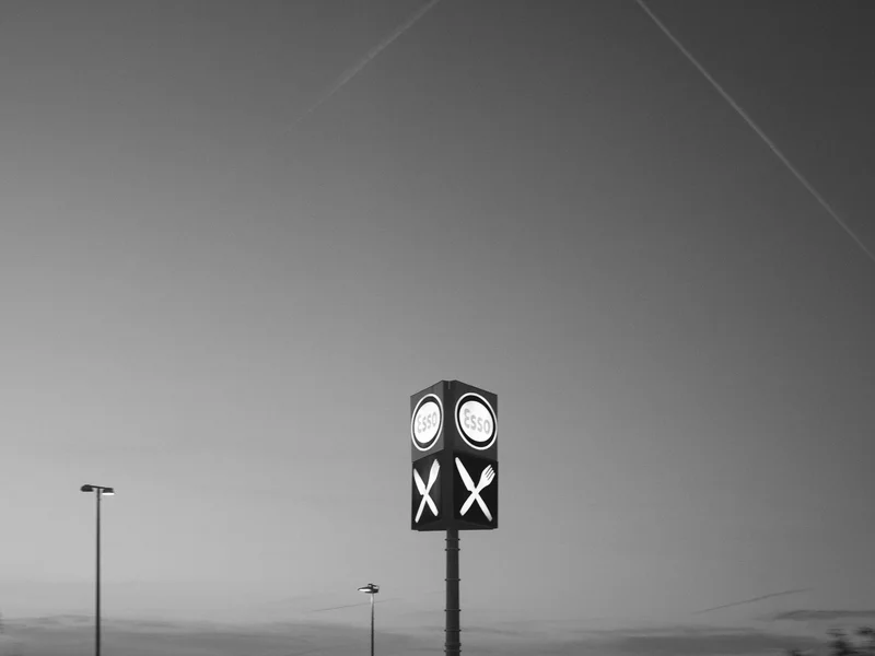 A tall signpost with the Esso logo and a cutlery icon against a dusky sky.