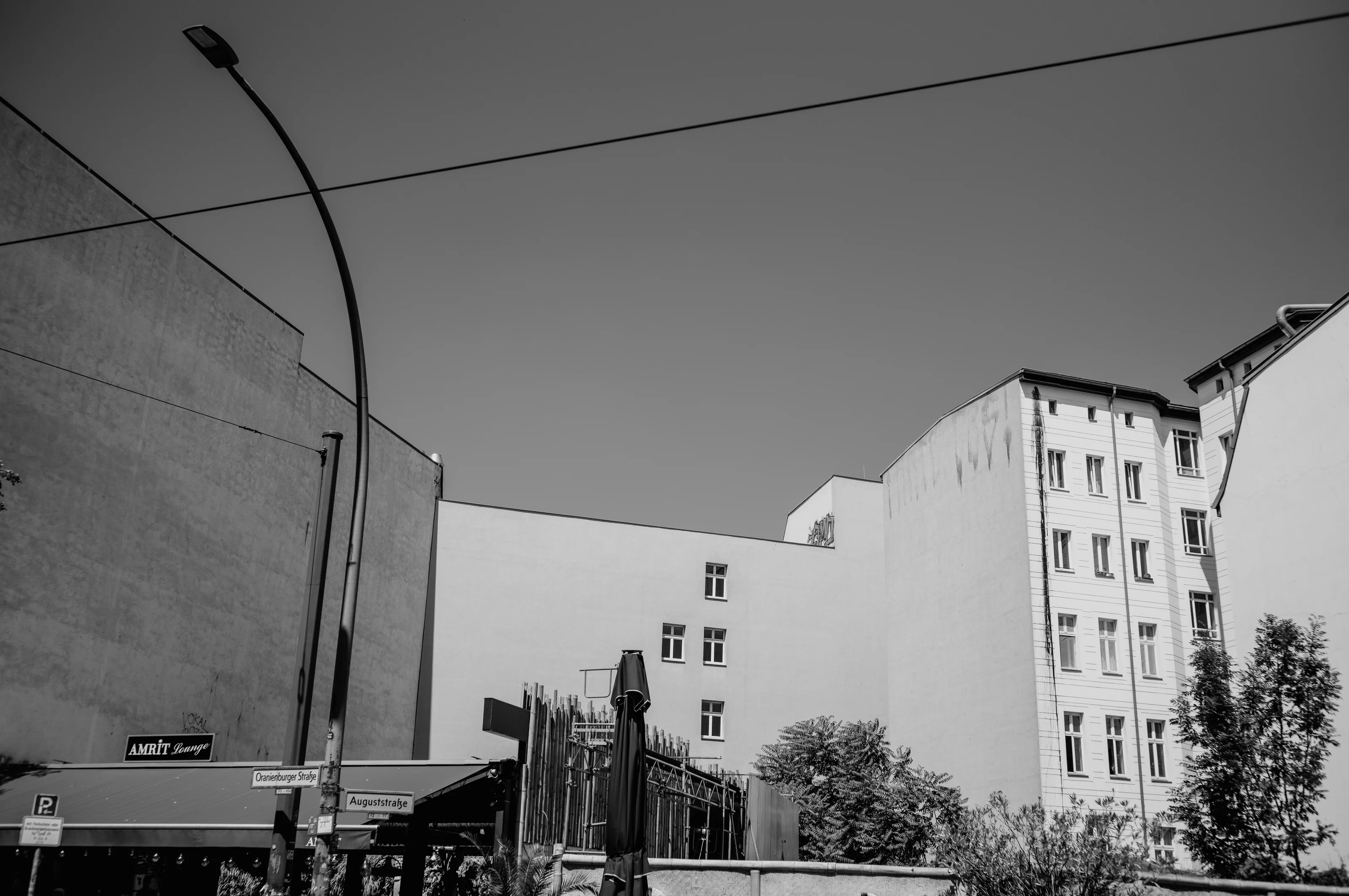 Black and white urban scene with tall buildings, a streetlight, and street signs.