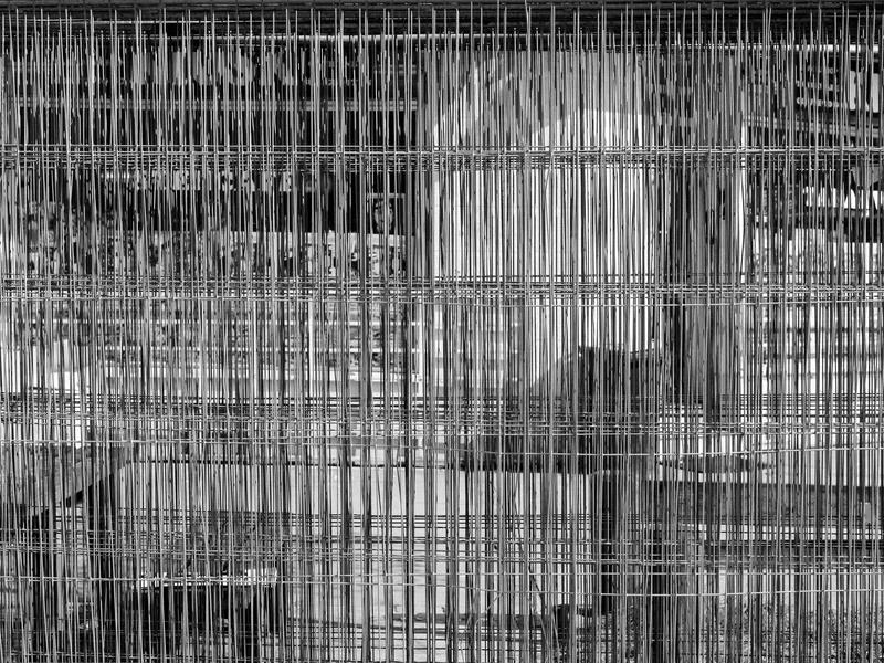 Black and white image of a complex grid of vertical and horizontal metal rods with abstract patterns.