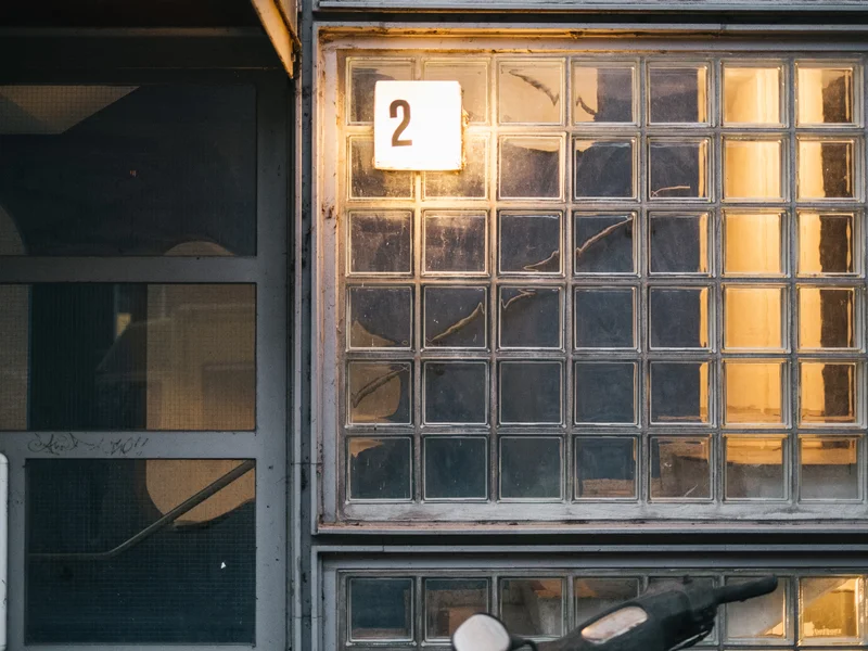 A numbered window with a sign '2' above a grid of textured glass blocks.