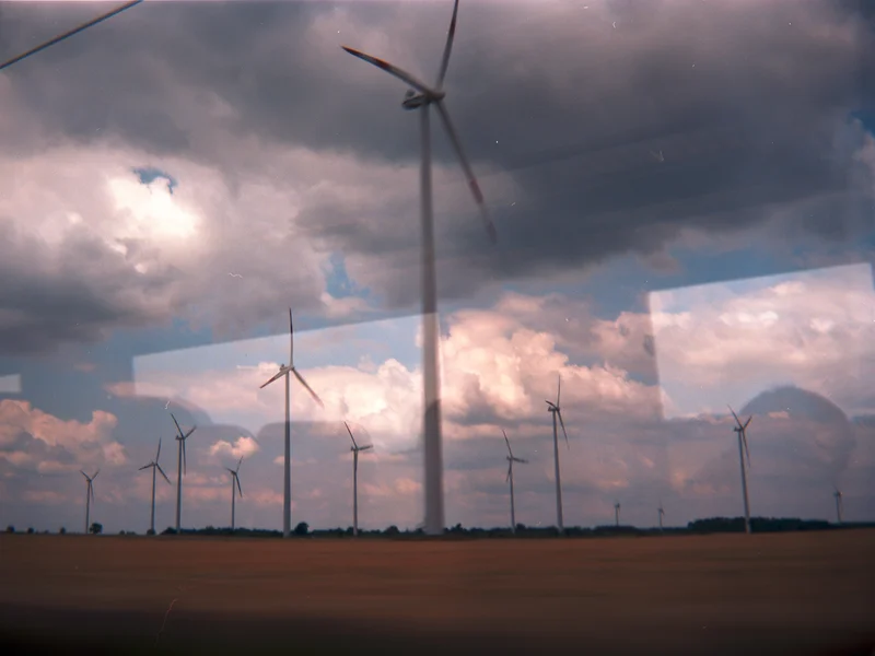 Wind turbines in a vast field under a cloudy sky.