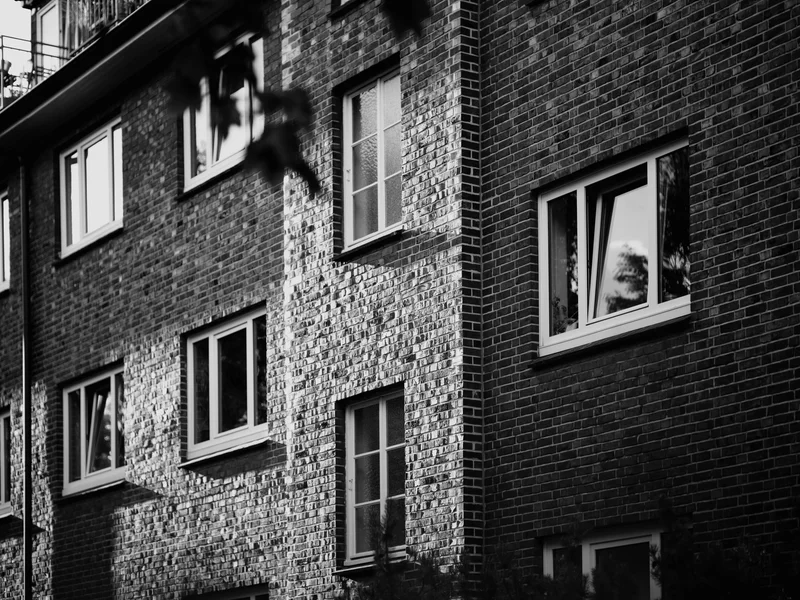 Black and white photo of a brick building with several windows.