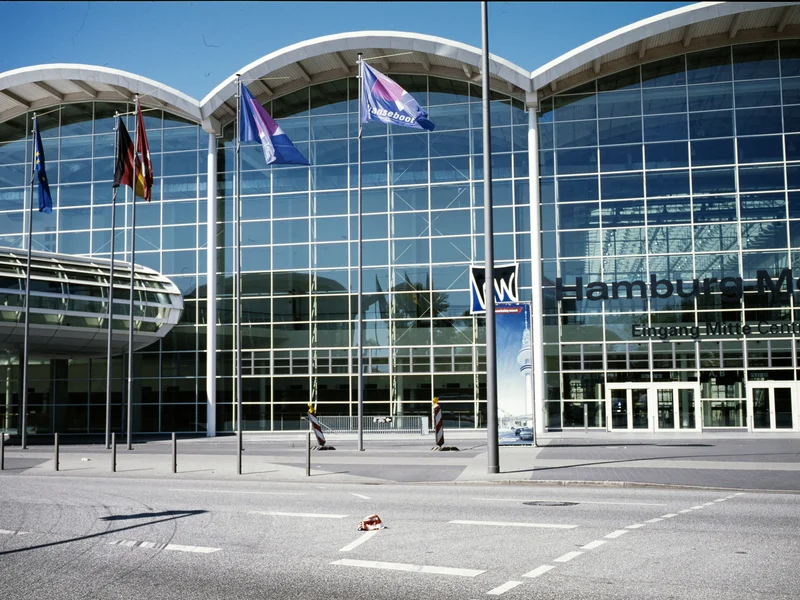 Entrance to Hamburg Messe with flags and large glass facade.