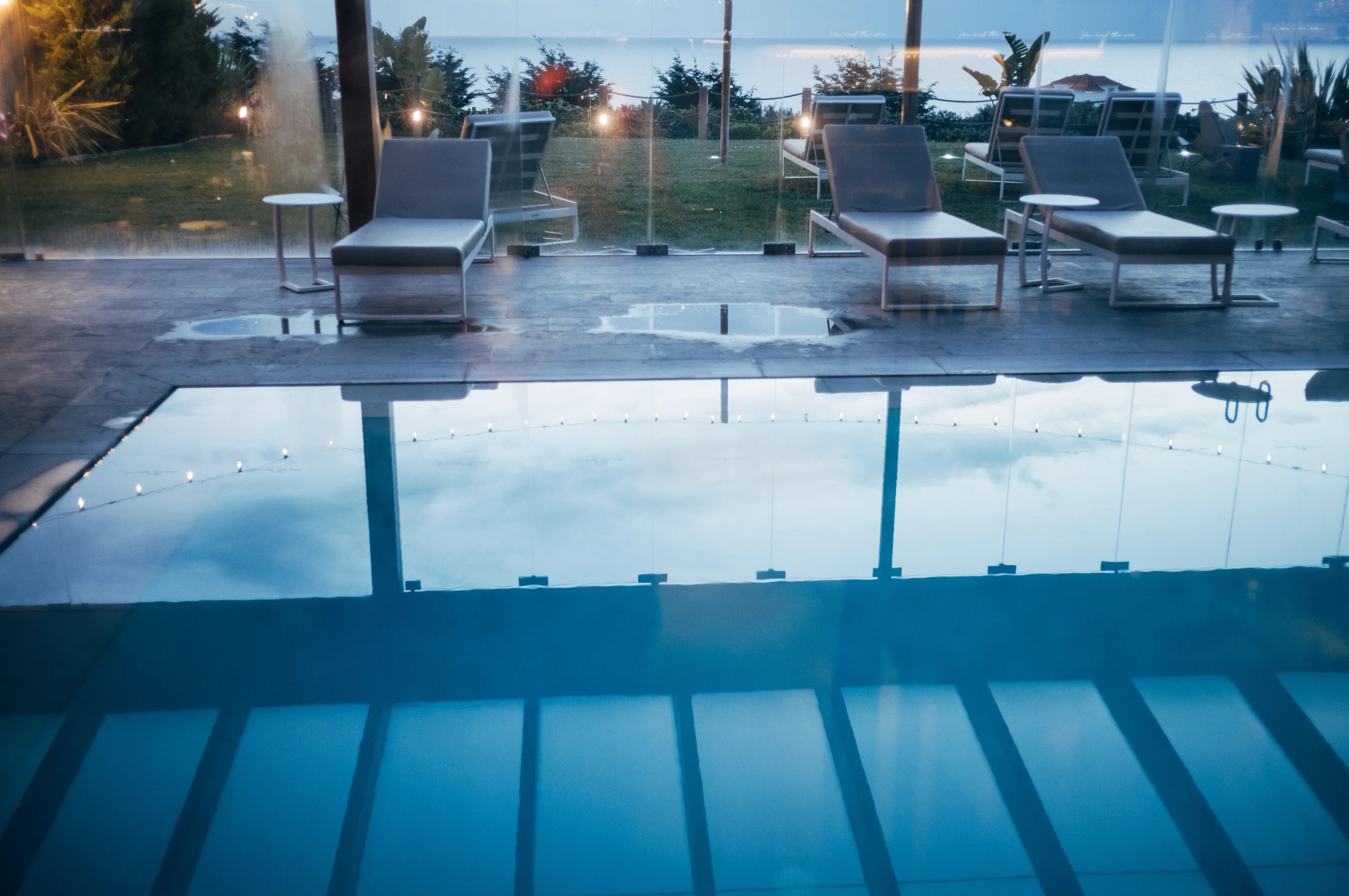 A serene outdoor pool area with lounge chairs overlooking the ocean.